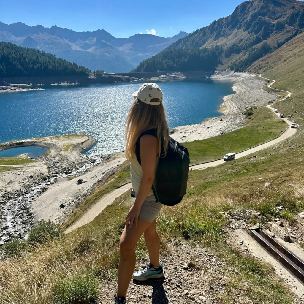 Person standing by Lago Ritom in Ticino, enjoying the breathtaking views of the alpine lake and surrounding mountains.